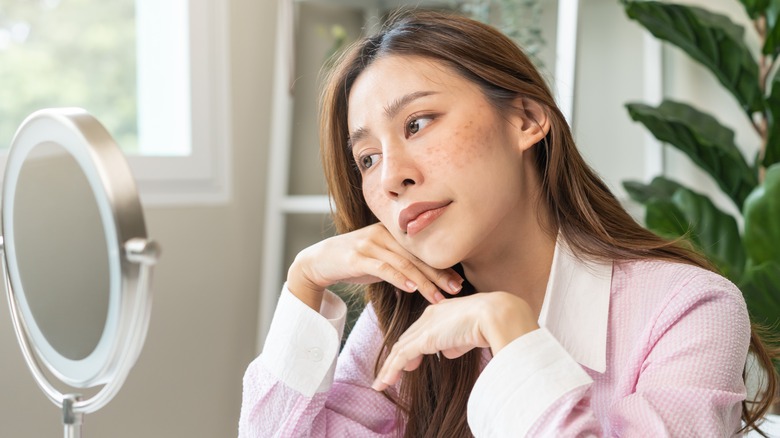 pensive young woman staring into mirror