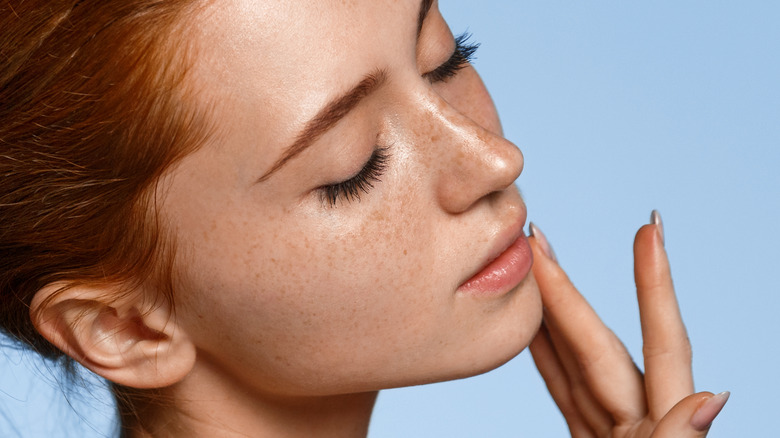 woman with freckles with eyes closed