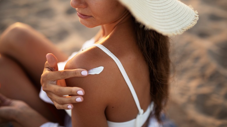 woman in hat using retinol sunscreen