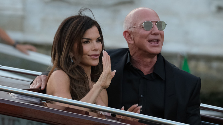 Jeff Bezos with his hand around Lauren Sánchez as she waves at guests at their wedding weekend