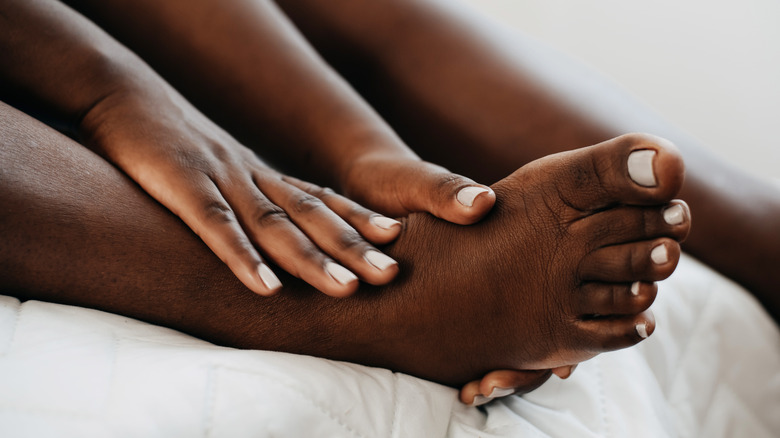 A person rubbing the soles of their bare feet with product.