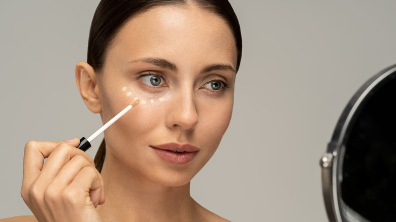 Woman applying makeup in the mirror