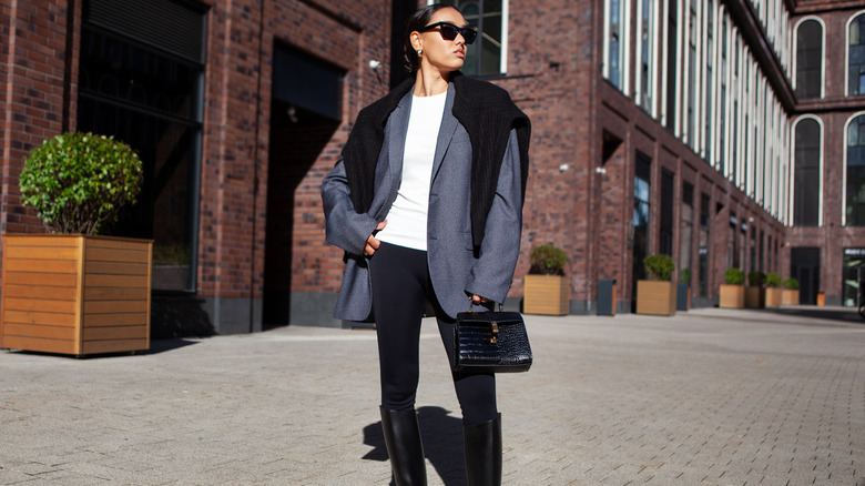 A woman wearing leggings, a blazer, and boots posing for a picture