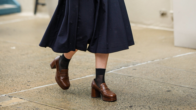 woman wearing brown platform heels with black socks and midi skirt