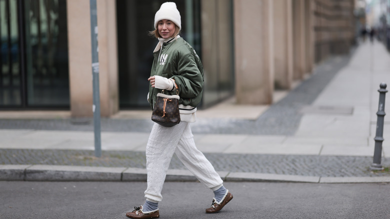 Woman wearing white hat and pants with green jacket