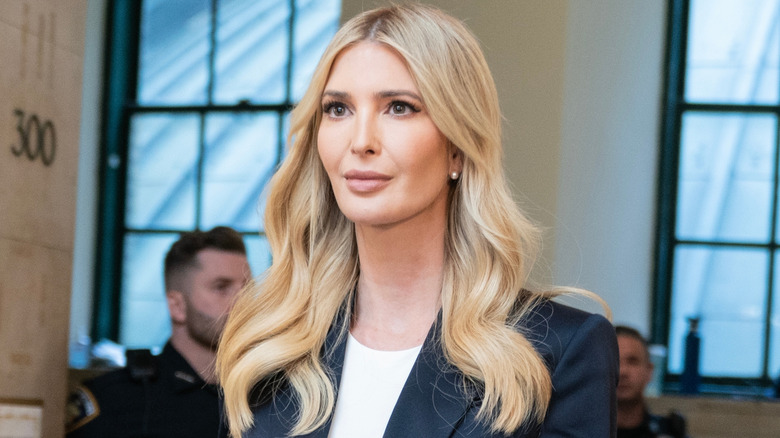 Ivanka Trump walks down a hallway wearing a navy blue suit jacket