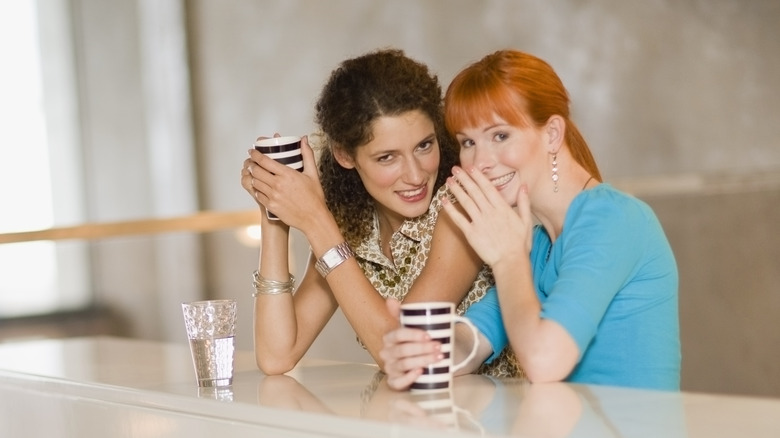 Co-workers whisper to one another