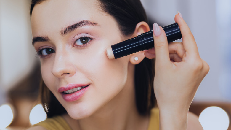 Woman applying stick concealer