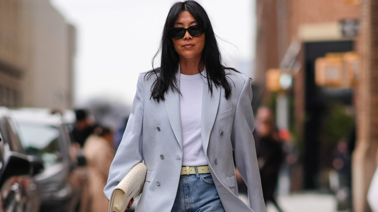 A woman dressed in minimal basics with a butter-yellow clutch and sunglasses