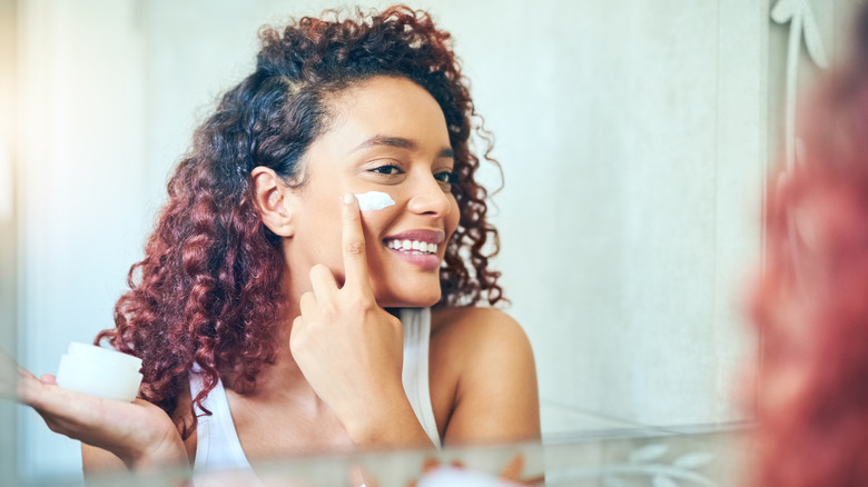 Woman applying skincare product to face
