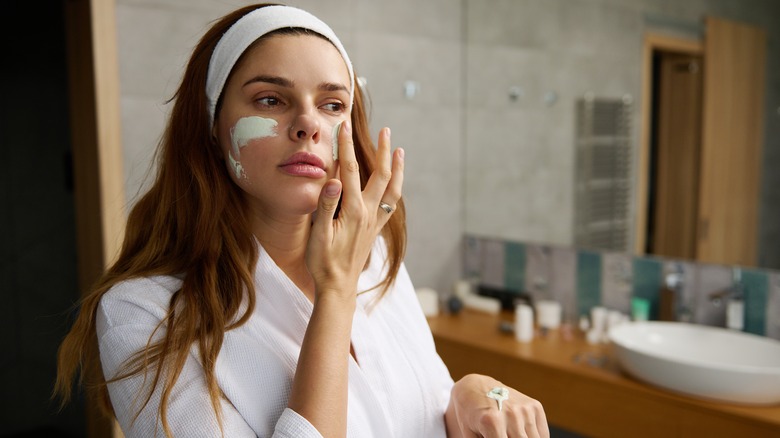 woman applying face mask with fingers