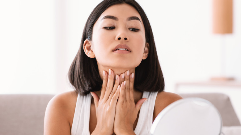A woman applying cream on her neck 