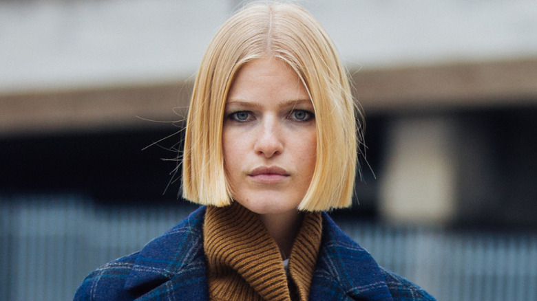 A woman with a blunt bob haircut wearing a turtleneck and coat