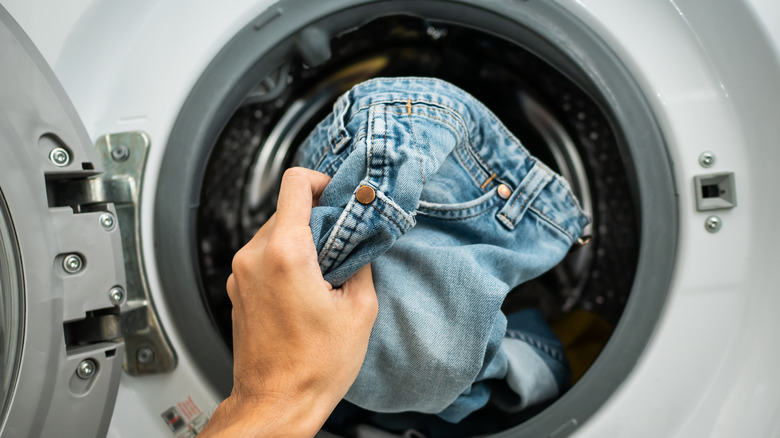Jeans being put into a washing machine 