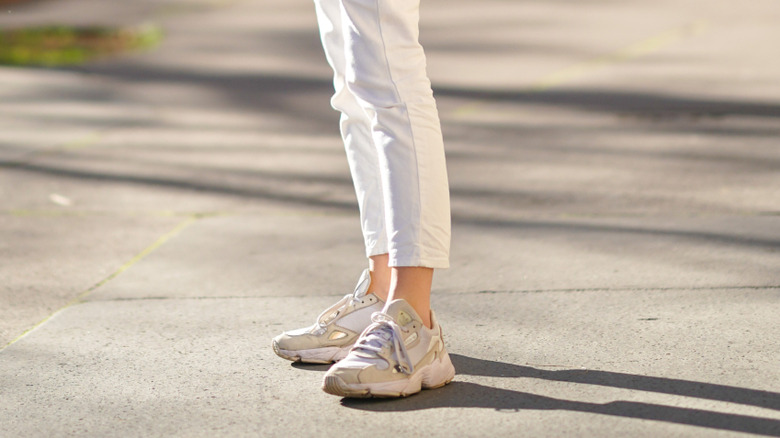 White cropped jeans and beige chunky sneakers on someone's feet