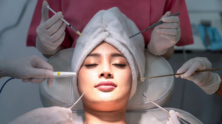A woman laying down with her eyes closed before an aesthetic procedure