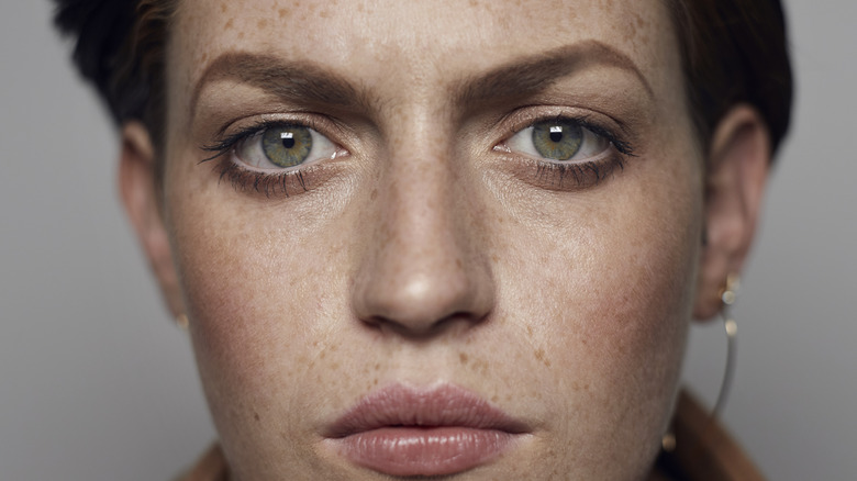 A non-binary person with piercing grey eyes