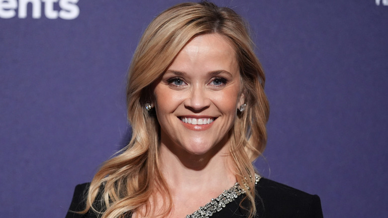 Reese Witherspoon posing in front of a media wall with brond waves