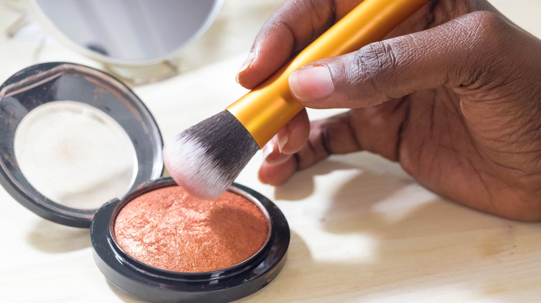 person dabbing brush onto highlighter