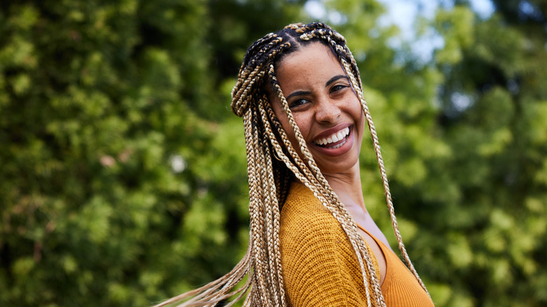 Black woman with middle part and braids twirling hair