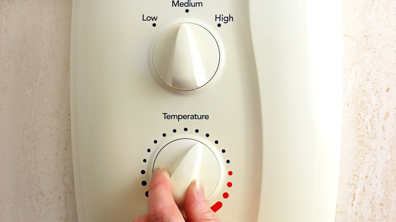 hand turning down shower thermostat
