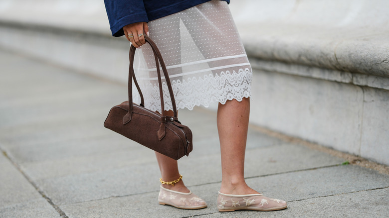 Someone wearing a white lace skirt with an intricate hemline