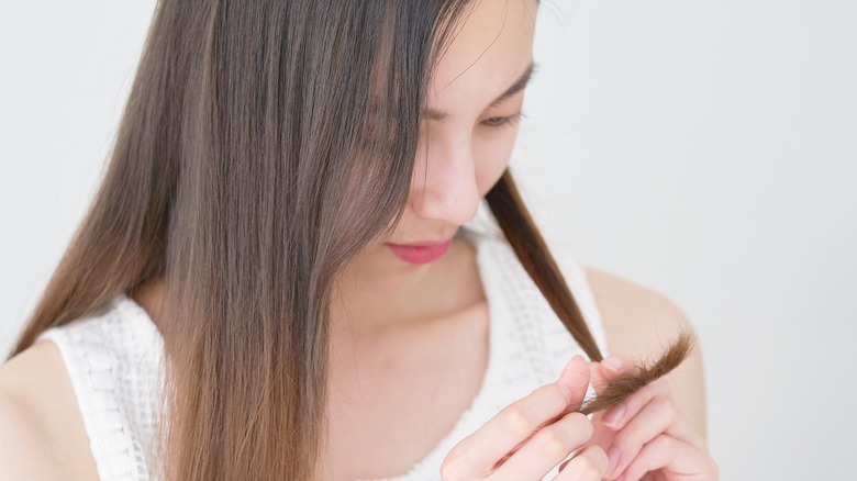 woman examines her hair