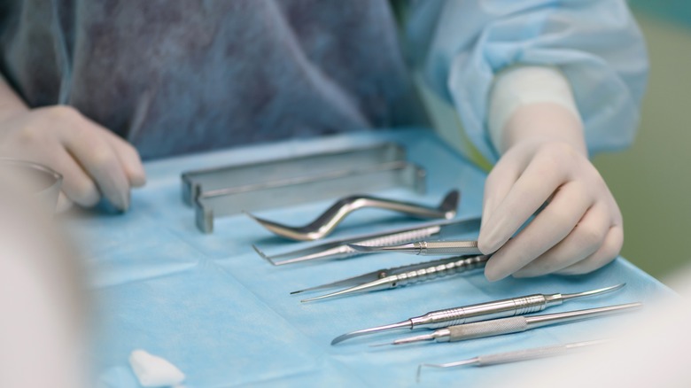 A gloved hand reaching for a surgical tool on a tray