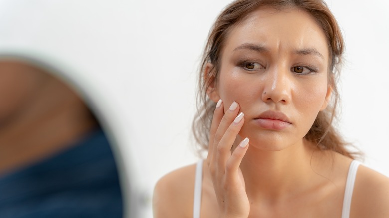 woman examining her face