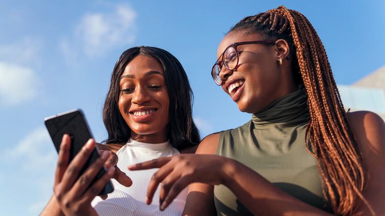 smiling friends looking at a phone