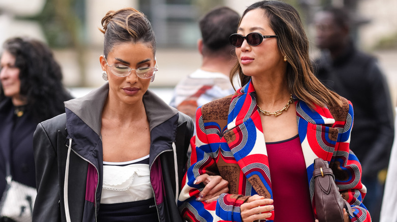 A woman wearing a windbreaker standing next to a woman wearing a colorful blazer coat
