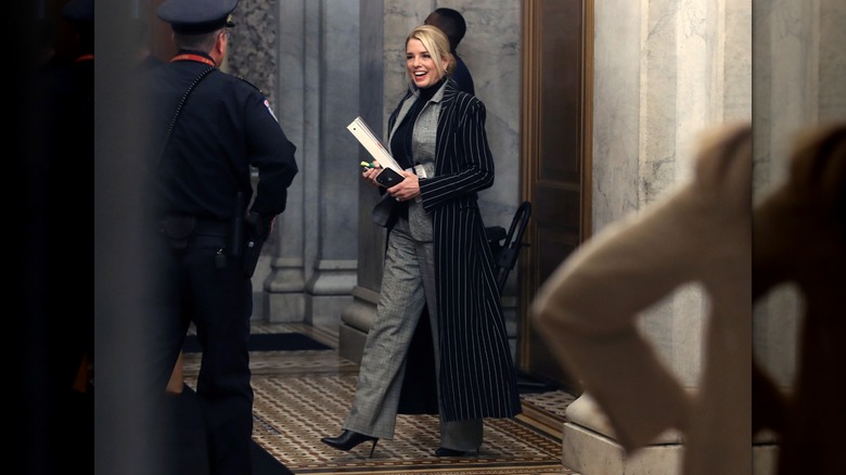 Pam Bondi wearing a plaid suit and turtleneck and pinstripe jacket