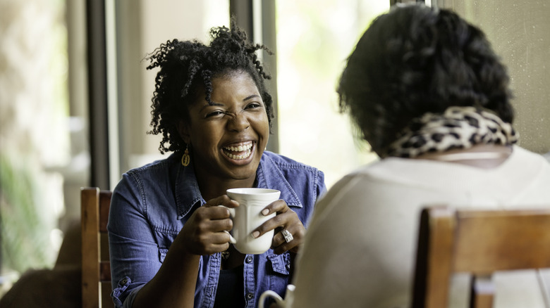 Two women laugh over coffee