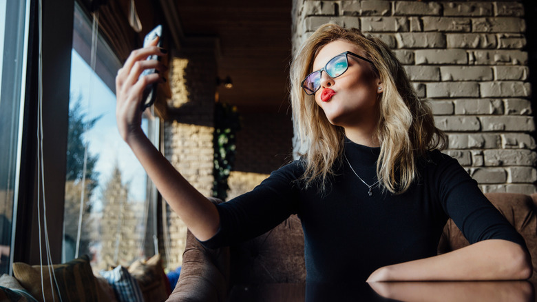 Woman taking selfie in front of bricks