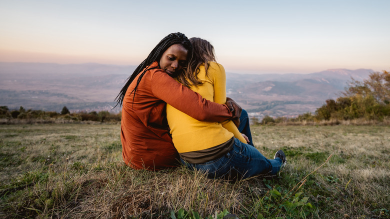 Friends embrace on a hillside