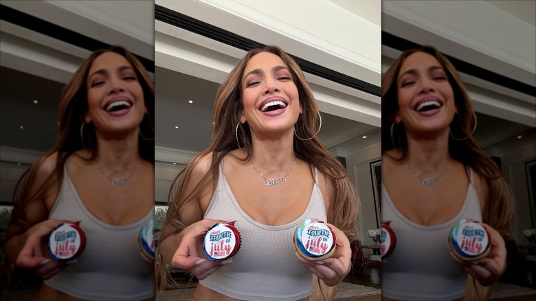 Jennifer Lopez smiles while holding fourth of July cupcakes