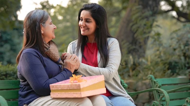 Woman giving a gift on park bench