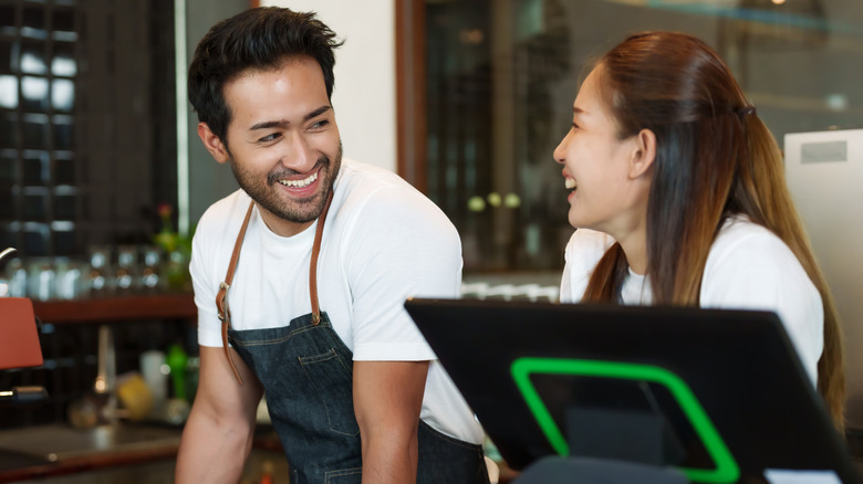 Two café employees smile at each other