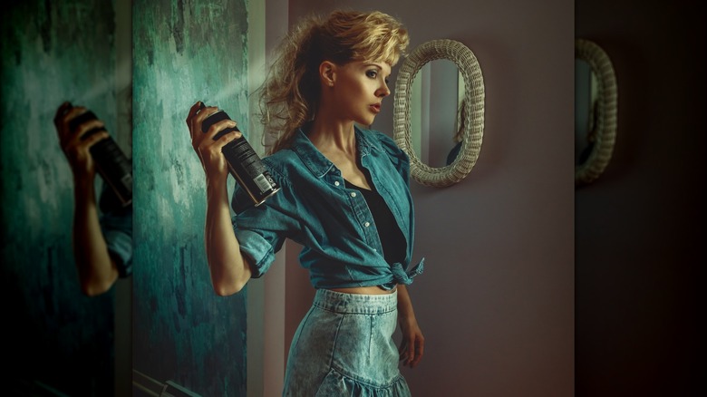 A woman applying hairspray