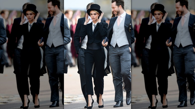 Cara Delevingne adjusting her top hat while wearing a suit at Princess Eugenie's wedding