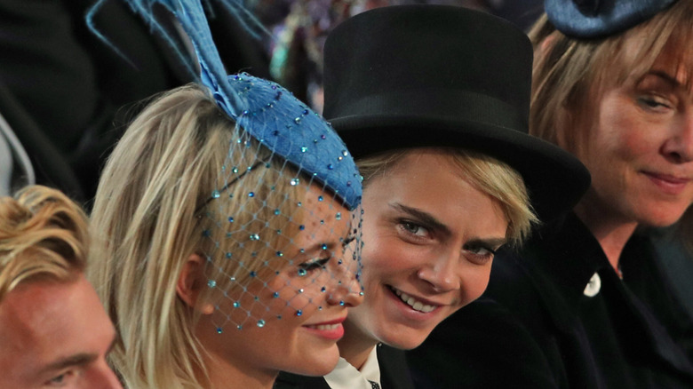 Cara Delevingne and Poppy Delevingne wearing a top hat and a fascinator, respectively, at Princess Eugenie's wedding