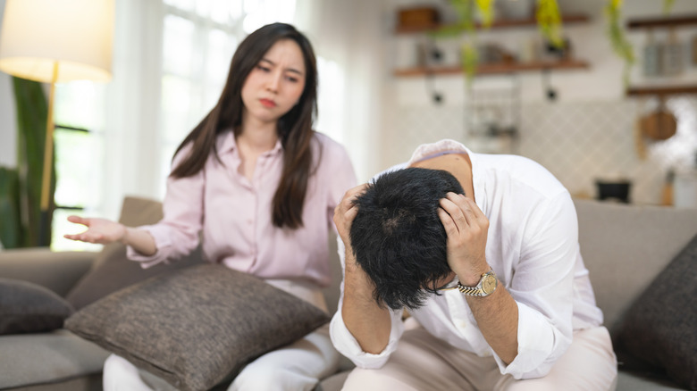 A couple arguing while sitting on a beige couch
