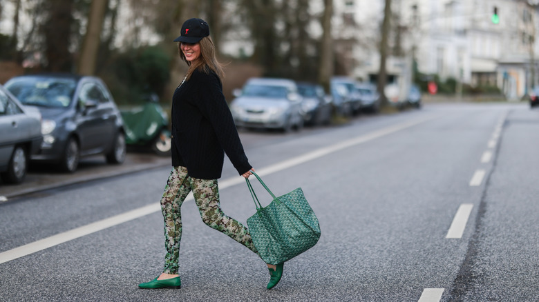 A woman wearing a crewneck cardigan and multi-colored leggings