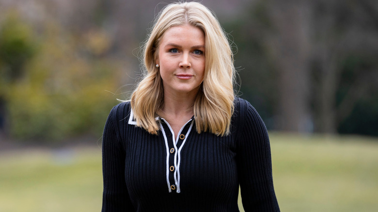 Karoline Leavitt walks up to a press briefing wearing a black sweater dress