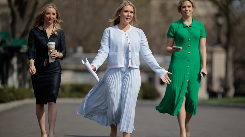Karoline Leavitt wearing an unstylish full midi blue dress with a matronly sweater while walking up to a group reporters