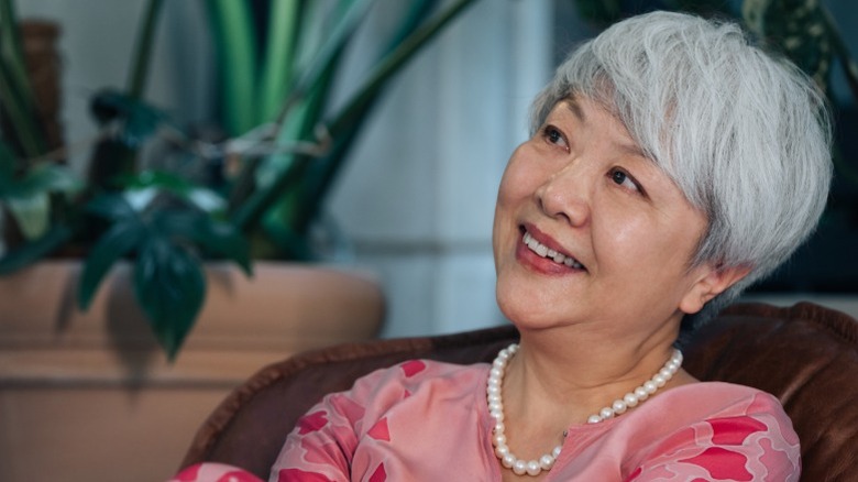 A woman with a soft pixie hairstyle gazes at something