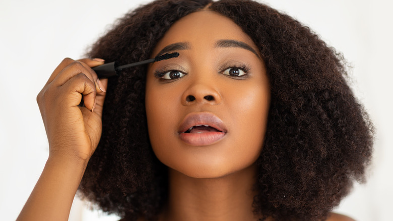 Black woman applying mascara