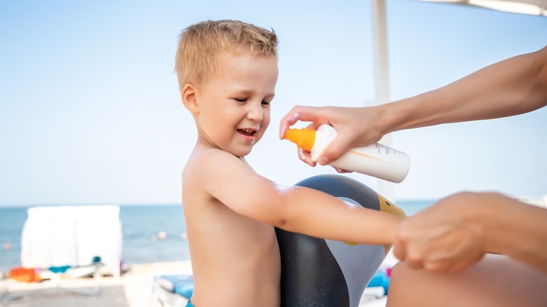 adult applying spray sunscreen