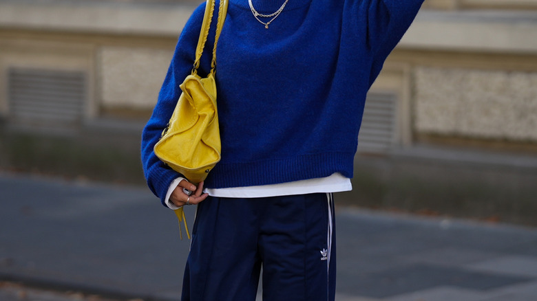 A woman wearing a blue sweater and track pants