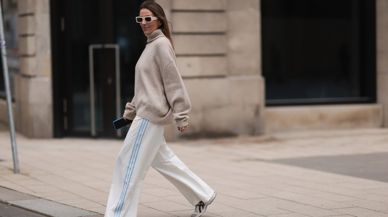 A woman wearing a baggy sweater and track pants